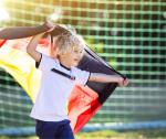 Junge im Fußballtrikot hält Deutschlandflagge